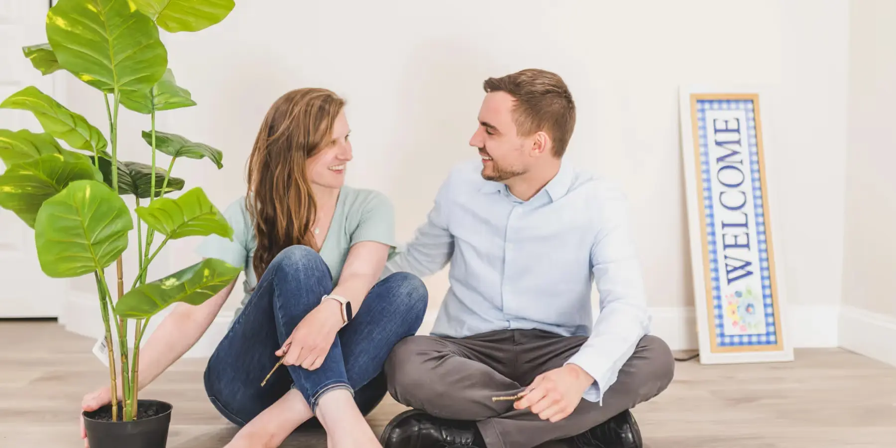 Paar sitzt glücklich auf dem Boden ihrer neuen leeren Wohnung