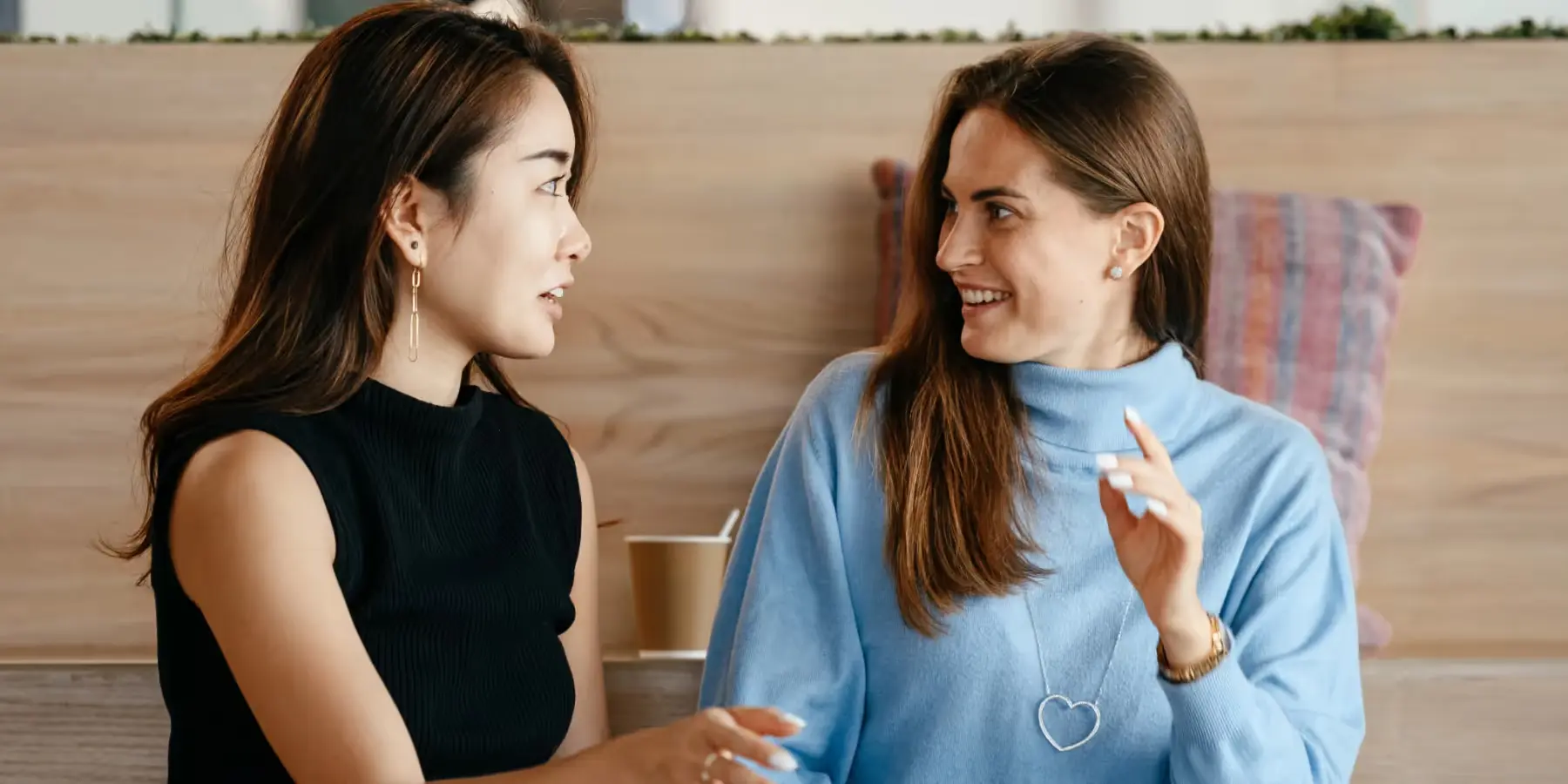 Zwei Frauen lächeln sich beim Gespräch an