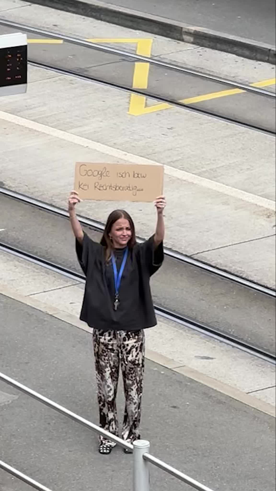 Eine Frau hält mitten auf der Strasse ein Schild.
