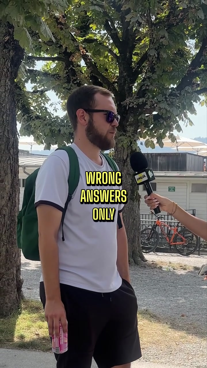 Ein Mann mit Rucksack wird im Freien von einer Frau mit Emilia-Mikrofon interviewt; Text „Wrong answers only“.