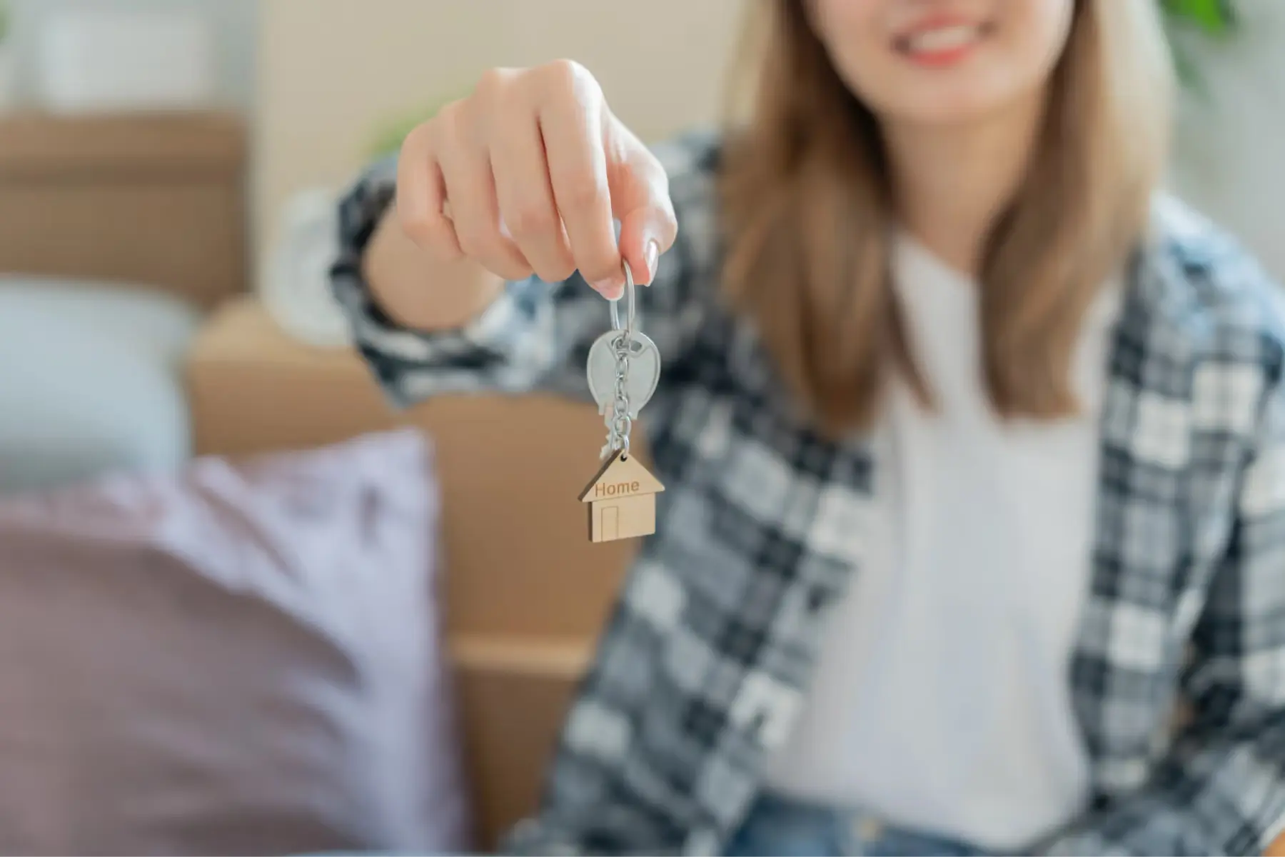Jeune femme souriante tient une clé avec porte-clé Home