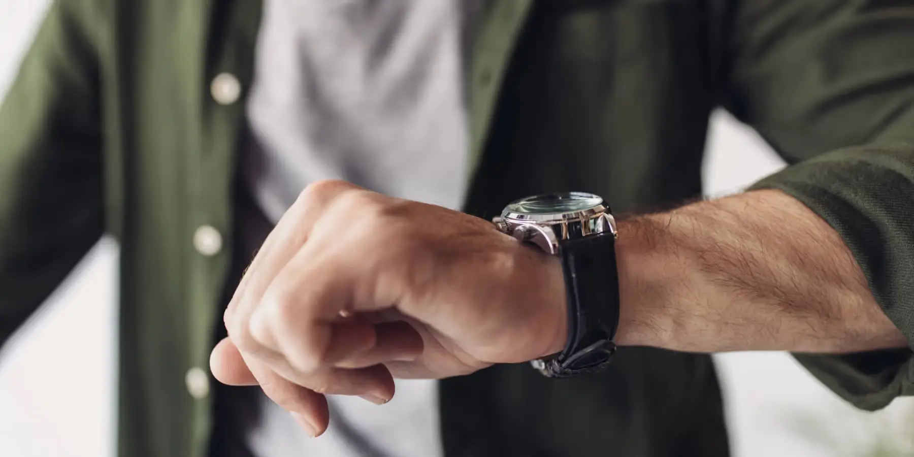 Mann schaut auf seine Armbanduhr