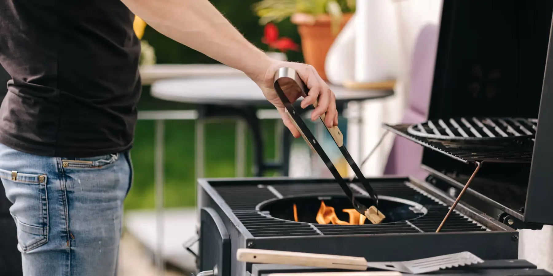 Personne utilise des pinces sur un barbecue allumé en extérieur