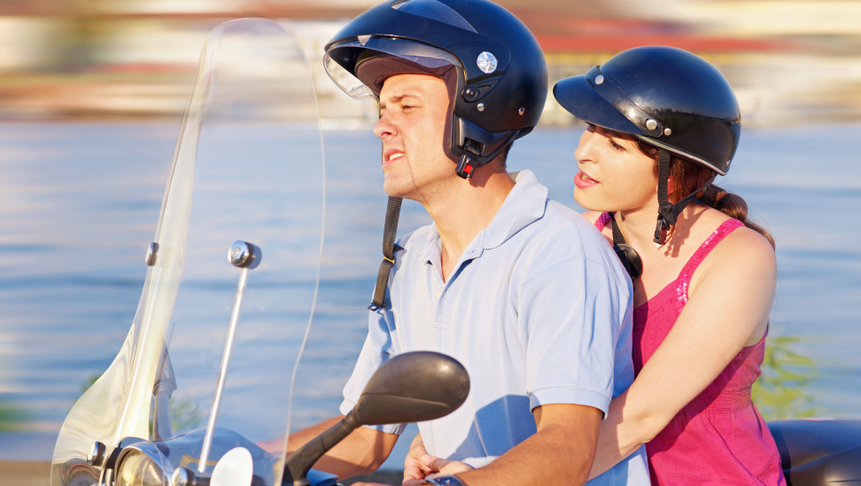 Pärchen mit Helm auf Motorroller